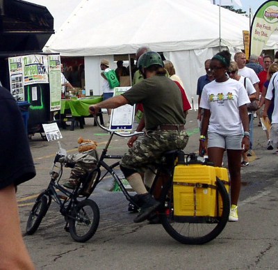 [Brett and the stuffed bear riding the watergun bike designed for an adult and a small rider.]